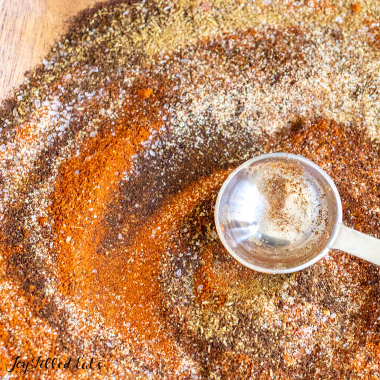 chili seasoning recipe on wood plate with measuring spoon close up