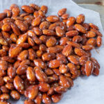 keto candied almonds recipe showing shiny glazed almonds on wax paper close up