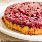 keto cranberry cake recipe on a cake plate showing upside down cranberry topping