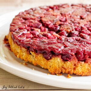 keto cranberry cake recipe on a cake plate showing upside down cranberry topping
