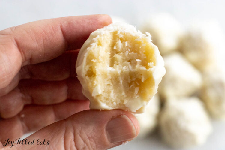 hand holding one of the coconut cream truffles with a bite missing