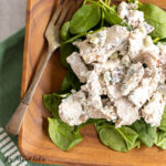 blue cheese chicken salad recipe close up on a bed of spinach on a wood plate