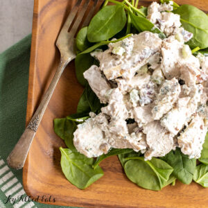 blue cheese chicken salad recipe close up on a bed of spinach on a wood plate