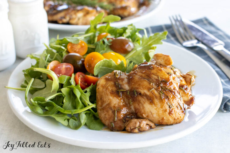 balsamic rosemary chicken thighs on dinner plate with arugula salad