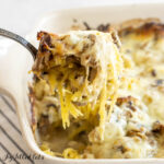 chicken tetrazzini casserole being lifted from baking dish with a large serving spoon