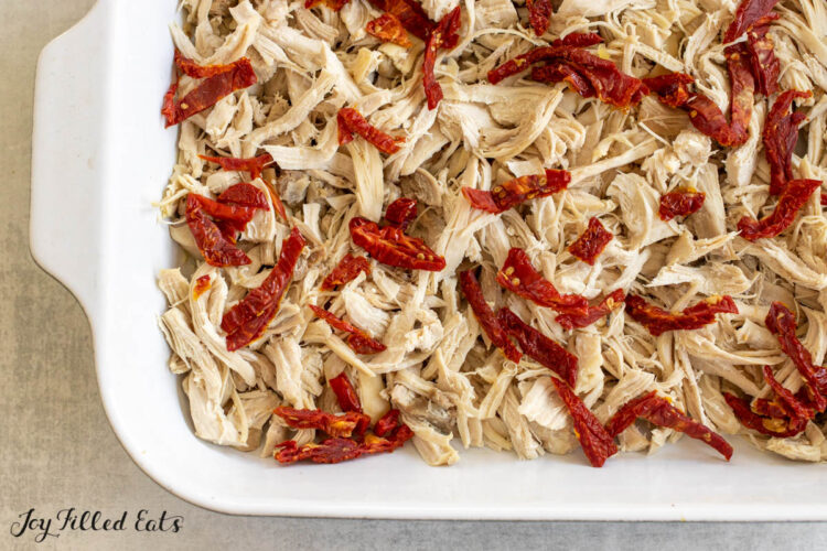 tomatoes on top of chicken in baking dish