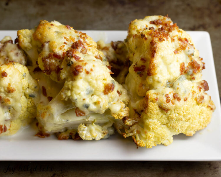 roasted cauliflower wedges with blue cheese sauce on white plate