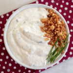 bacon cottage cheese dip in serving bowl from overhead  topped with extra bacon and fresh chives