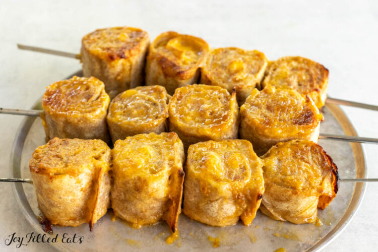 bbq chicken kebab rolls on skewers on plate