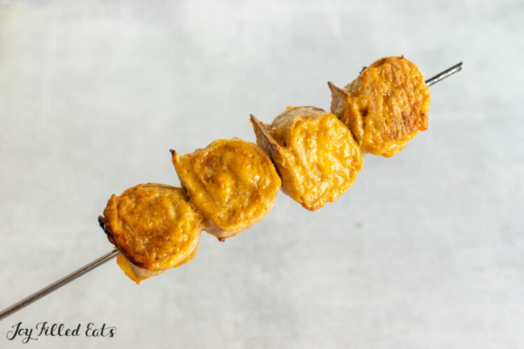 bbq chicken kebab rolls held up on a skewer