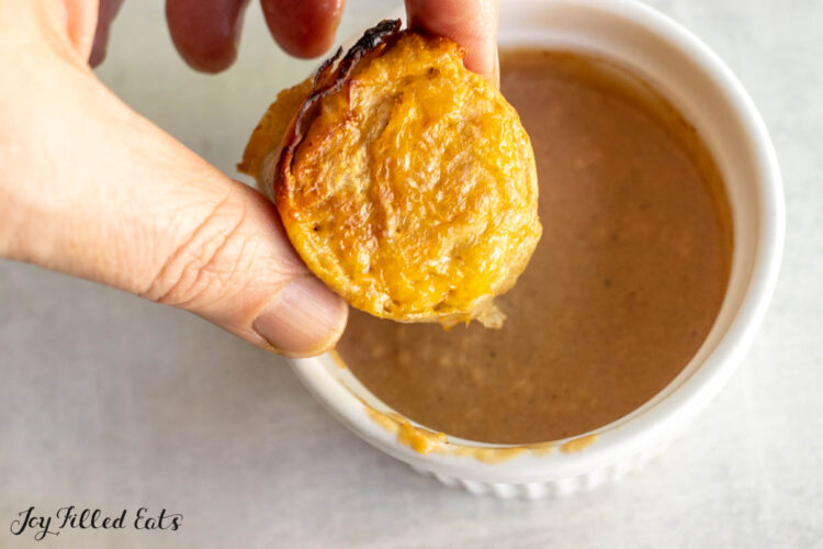 hand holding one of the bbq chicken rolls above a small ramekin of creamy bbq sauce