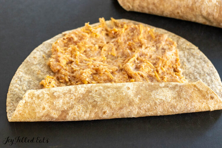 ground meat on tortilla being rolled up