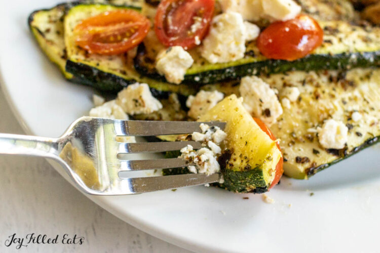 bite of zucchini, tomatoes, and feta cheese on a fork