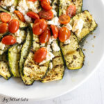 greek zucchini grilled with tomatoes and feta on a serving platter