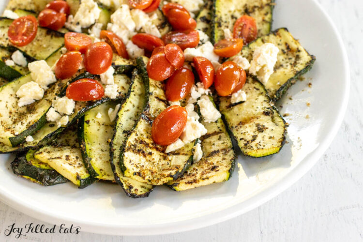 overhead shot of greek seasoning on grilled zucchini on a serving platter