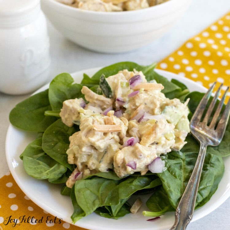 honey mustard chicken salad close up on bed of spinach with serving bowl behind