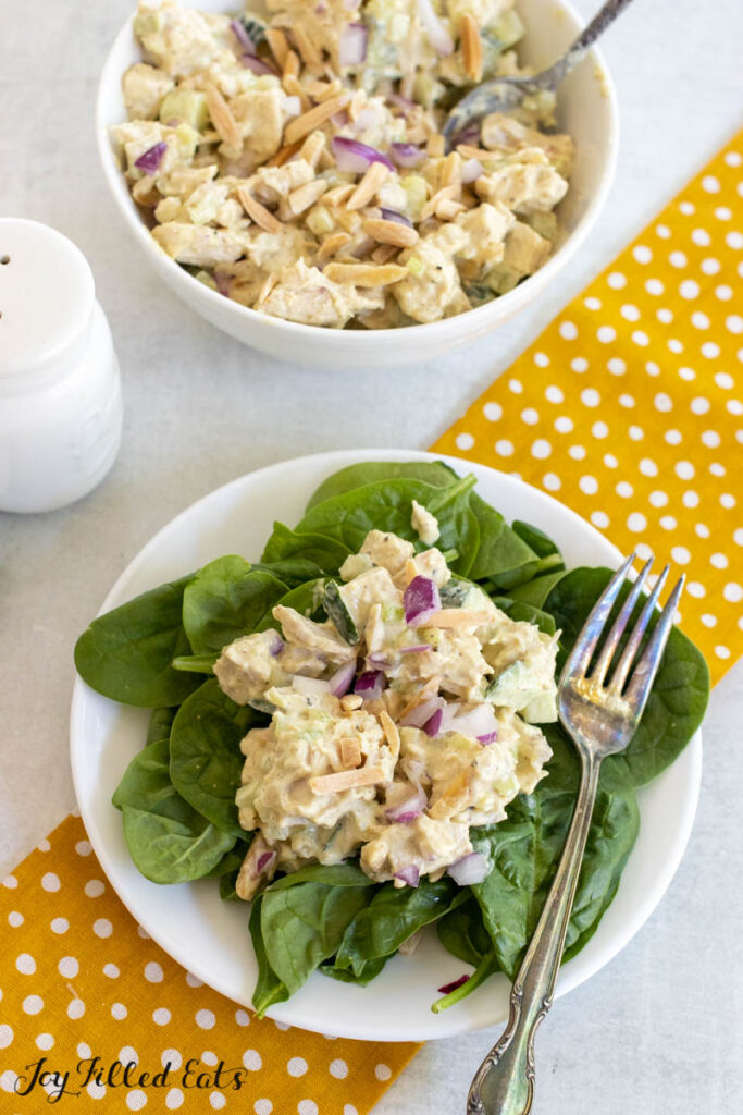 honey mustard chicken salad recipe on bed of spinach with serving bowl behind