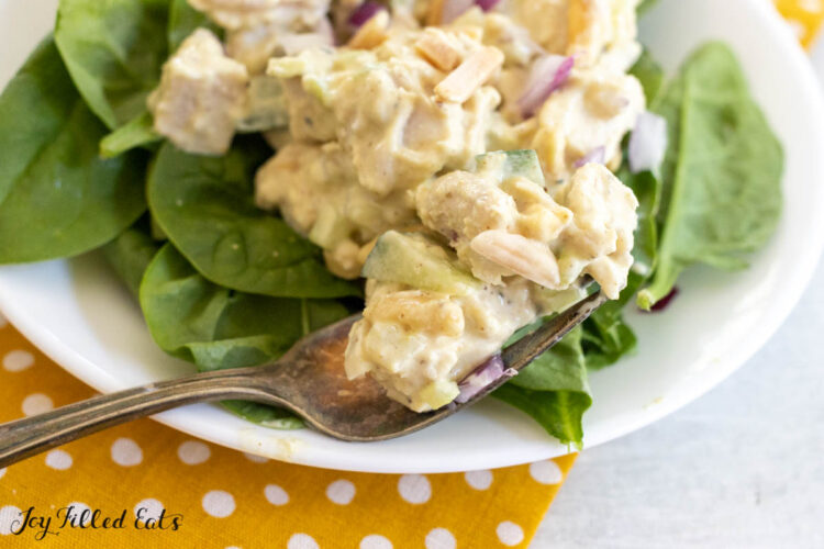 honey mustard chicken salad recipe on bed of spinach with bite on a fork