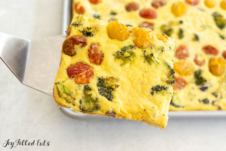 serving spatula holding up a piece of the sheet pan omelet