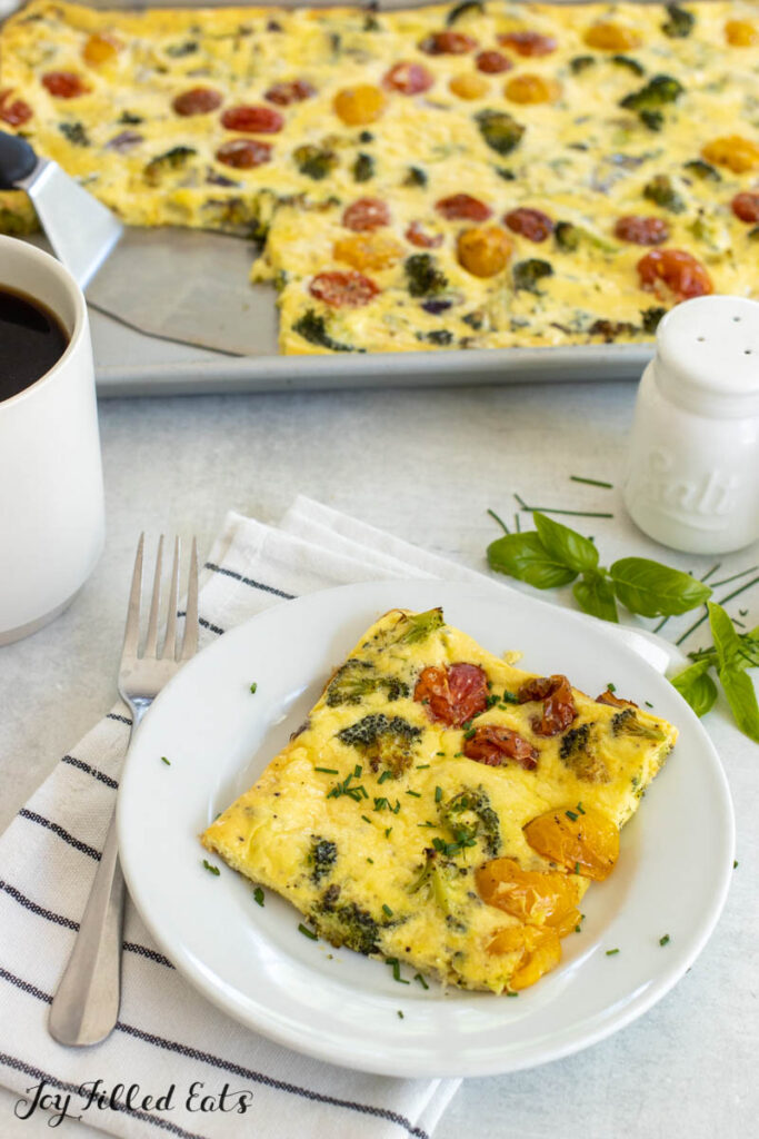 piece of the sheet pan omelet on a white plate with pan behind