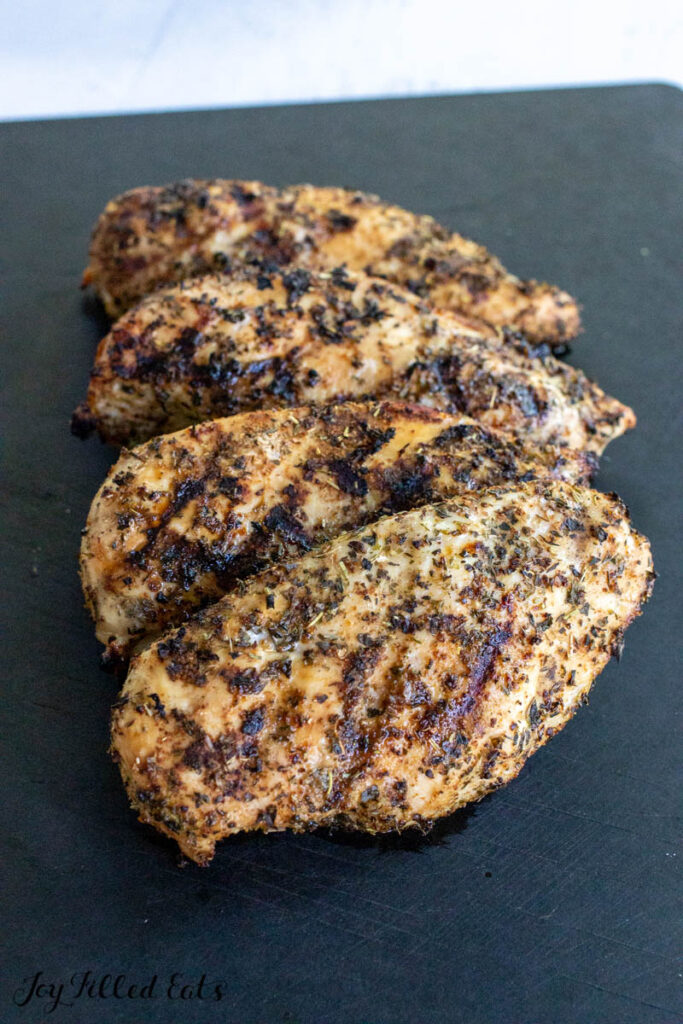 tuscan seasoning on grilled chicken breasts resting on cutting board
