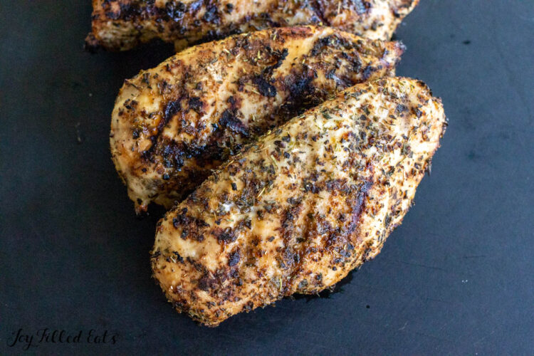 tuscan grilled chicken breasts resting on cutting board