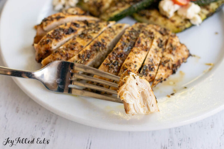 bite of tuscan chicken on fork resting on dinner plate