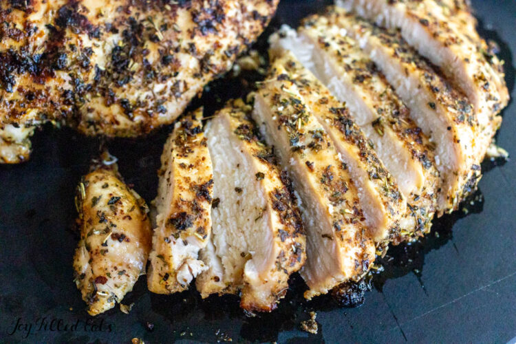 tuscan grilled chicken breasts sliced and whole on cutting board