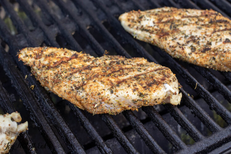 chicken breasts half cooked on grill