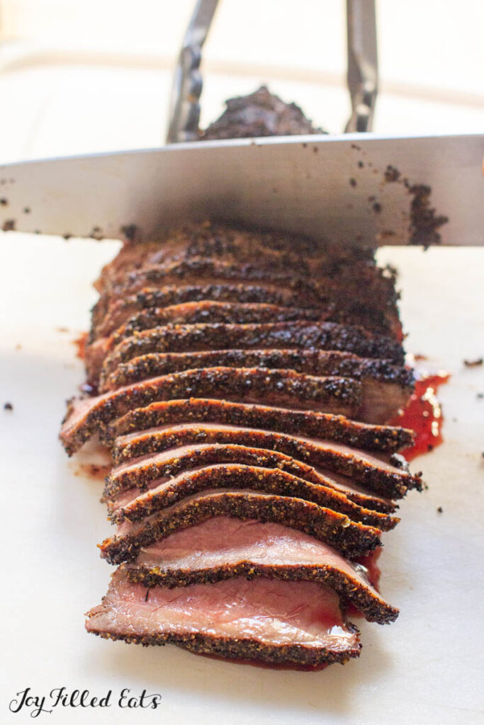 london broil with coffee dry rub being sliced with large knife