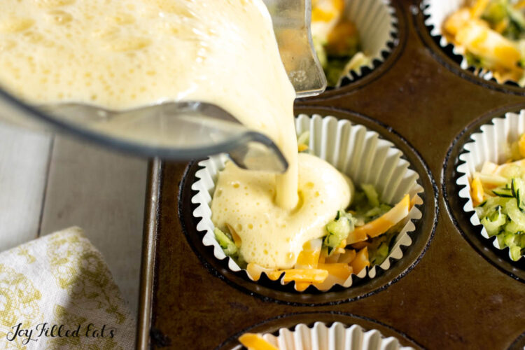 mixed eggs being poured over zucchini and cheese