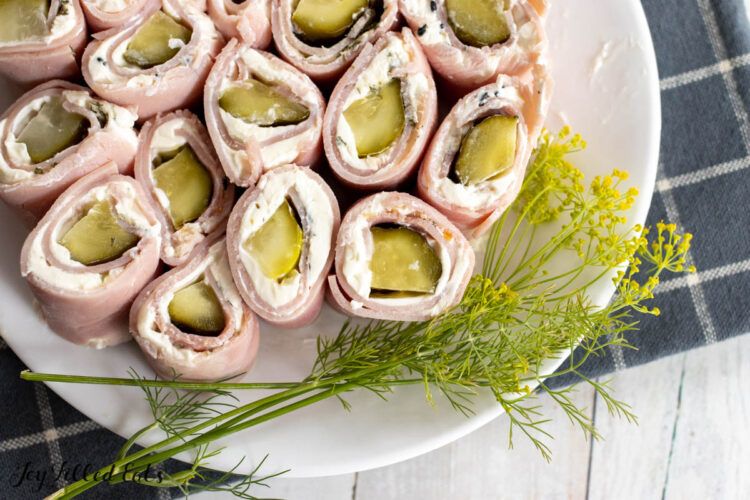 pickle rolls ups with ham and cream cheese on a serving plate with fresh dill