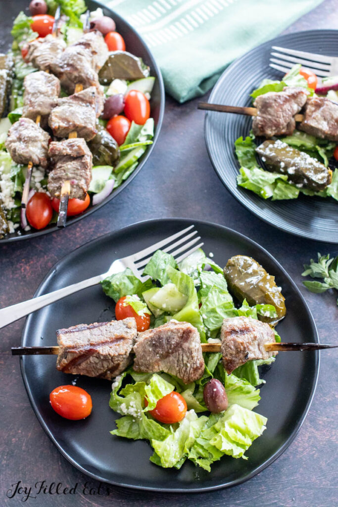 steak salad served on small plate with large bowl behind