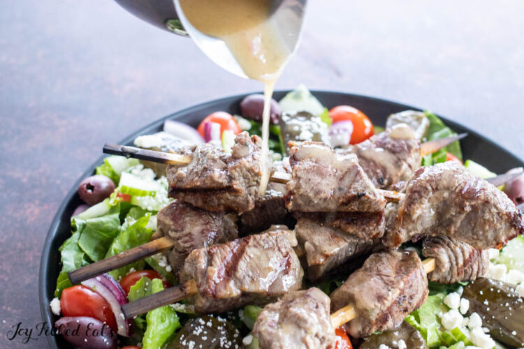 dressing being drizzled on mediterranean steak salad recipe