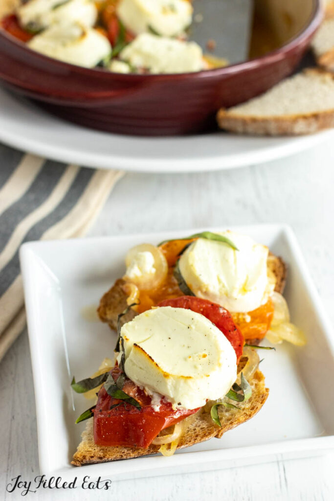 baked goat cheese on bread with platter surrounded by sourdough toasts behind