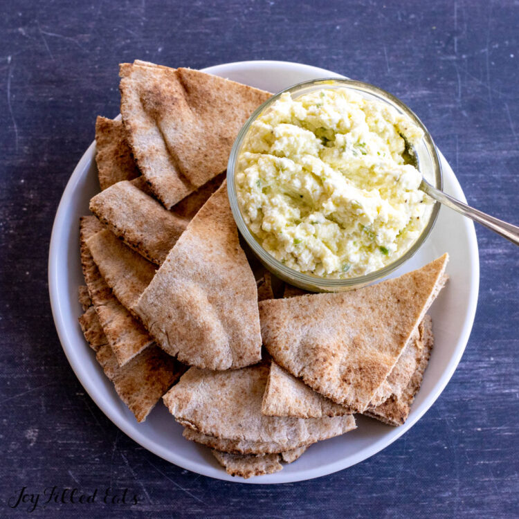 overhead shot of plate with feta dip in a bowl next to pita