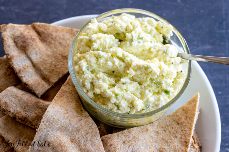 bowl with spicy feta dip on a plate with pita around